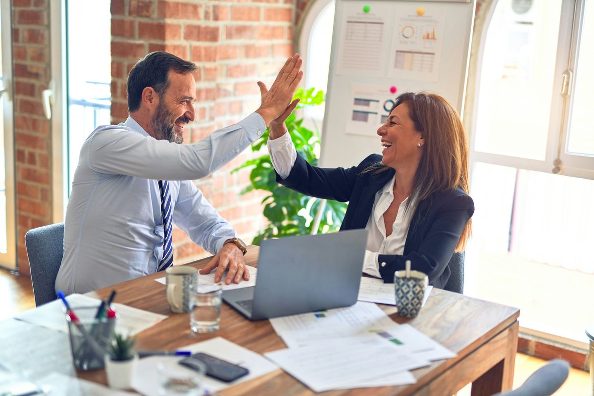 Two business colleagues high-fiving across a desk
